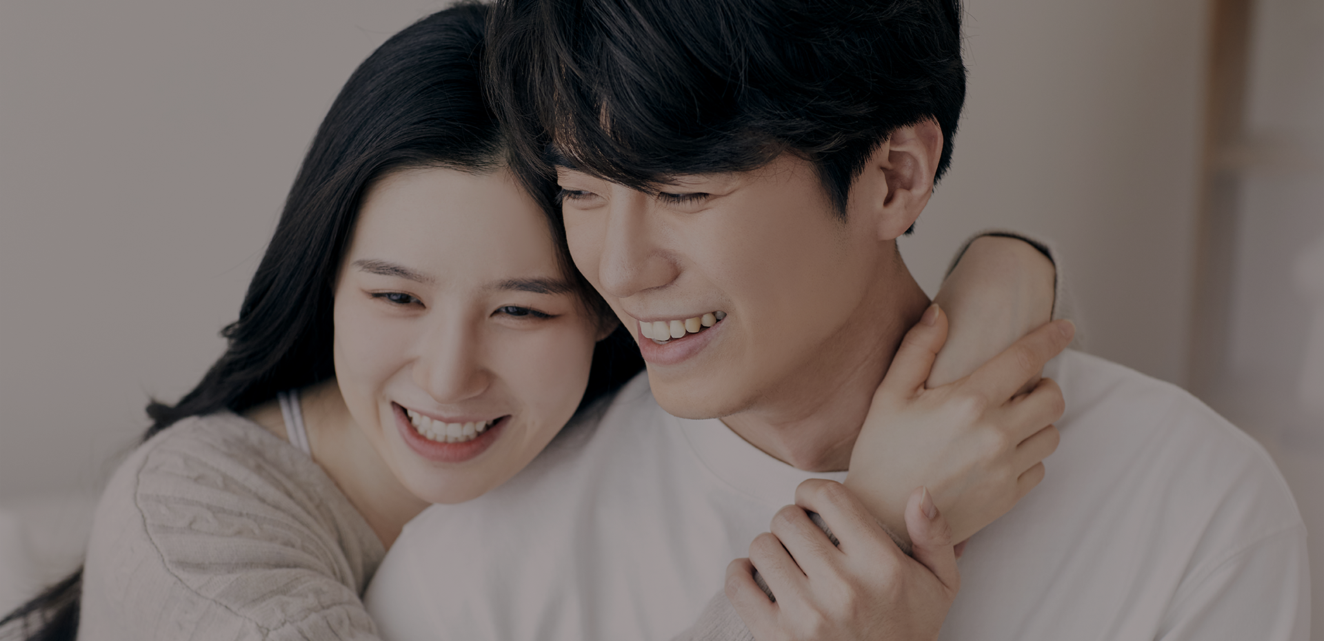서로 기대고 포옹하며 웃는 젊은 커플