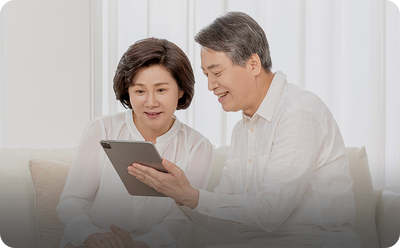 부부 건강검진 안내에 사용된, 태블릿을 함께 보는 중년 부부 사진