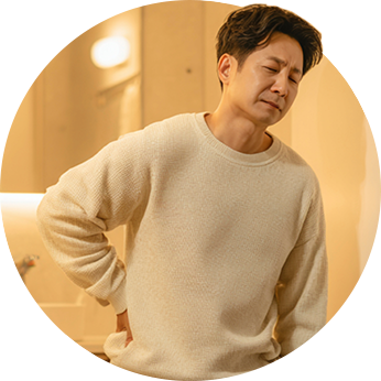 허리 뒤쪽을 짚고 불편한 표정을 짓는 남성