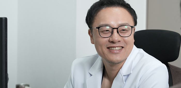 진료실에서 안경을 쓰고 미소 짓는 흰 가운의 의사