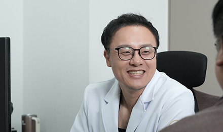 진료실에서 마주 앉은 사람에게 미소 짓는 의사