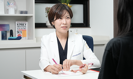 책상 위 여성 골반 모형을 두고 마주 앉은 사람과 상담하는 잠실 산비오의원 산부인과 전문의 허경은