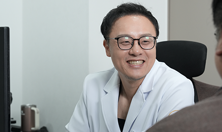 진료실에서 마주 앉은 사람을 바라보며 웃는 잠실 산비오의원 비뇨기과 전문의 정지윤