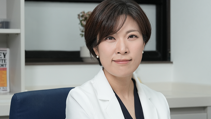 진료실에서 흰 가운을 입고 앉은 산부인과 여성 원장