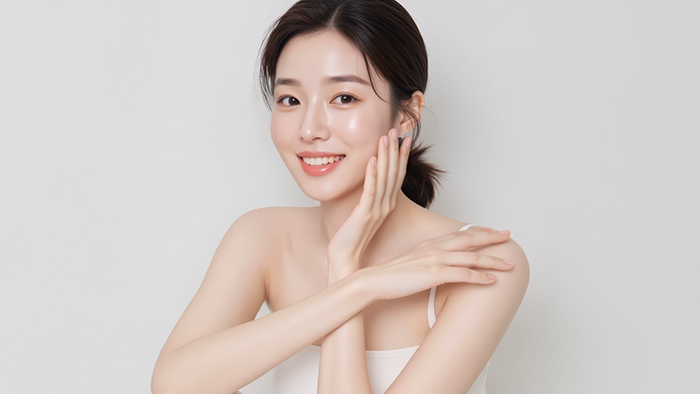 미소 지으며 한 손은 뺨, 다른 손은 어깨에 댄 여성