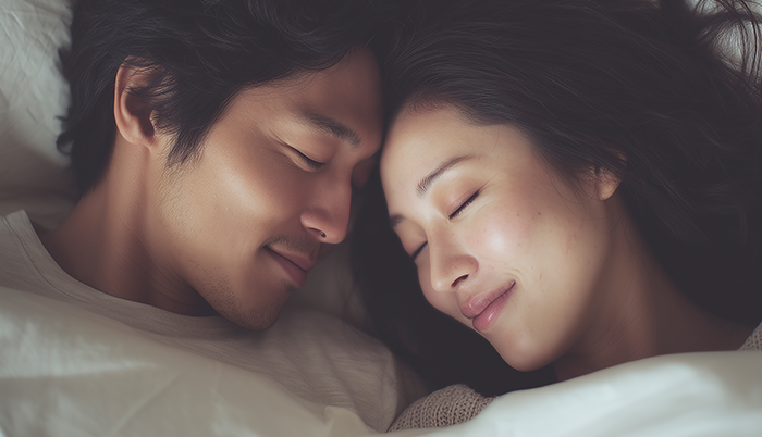 침대에 누워 눈을 감고 얼굴을 가까이 한 남녀
