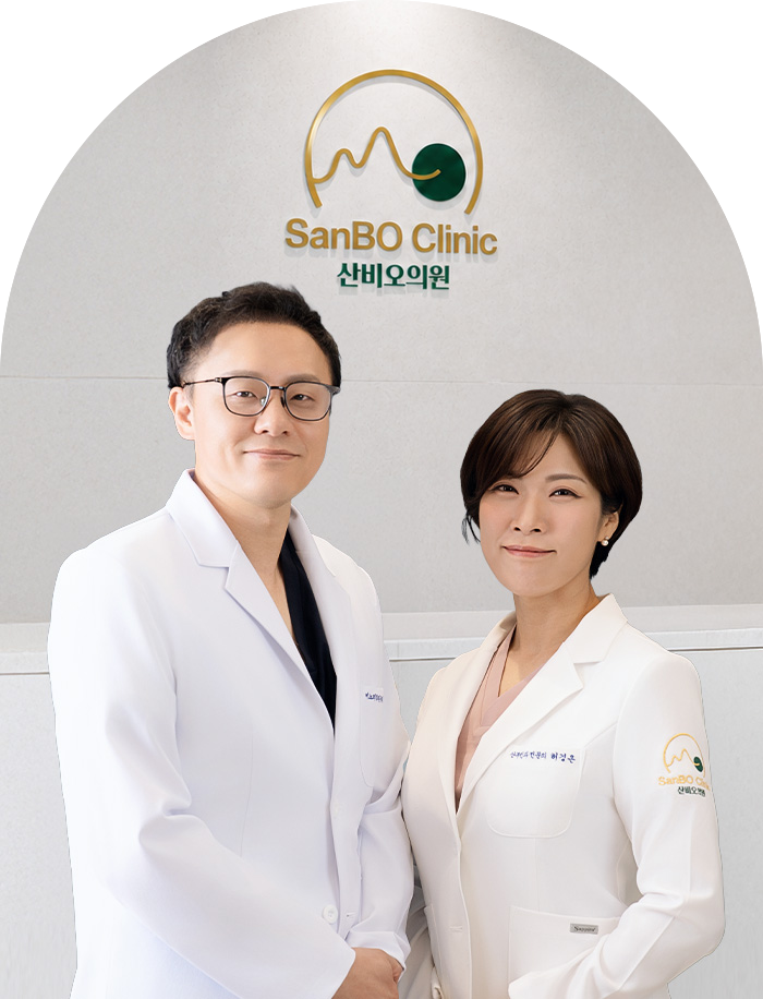산비오 로고 앞에 나란히 선 잠실 산비오의원 비뇨기과 전문의 정지윤과 산부인과 전문의 허경은
