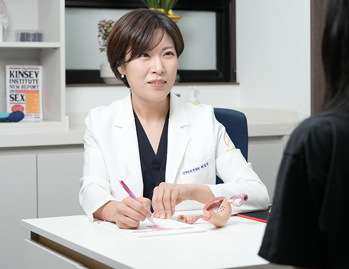 자궁 모형을 책상에 놓고 마주 앉은 사람과 상담하는 잠실 산비오의원 산부인과 전문의 허경은
