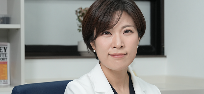 진료실에서 흰 가운을 입고 카메라를 바라보는 잠실 산비오의원 산부인과 전문의 허경은