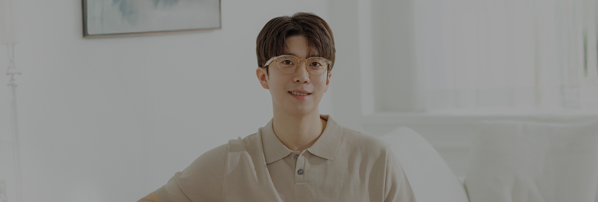 밝은 실내에서 안경을 쓰고 미소 짓는 남성
