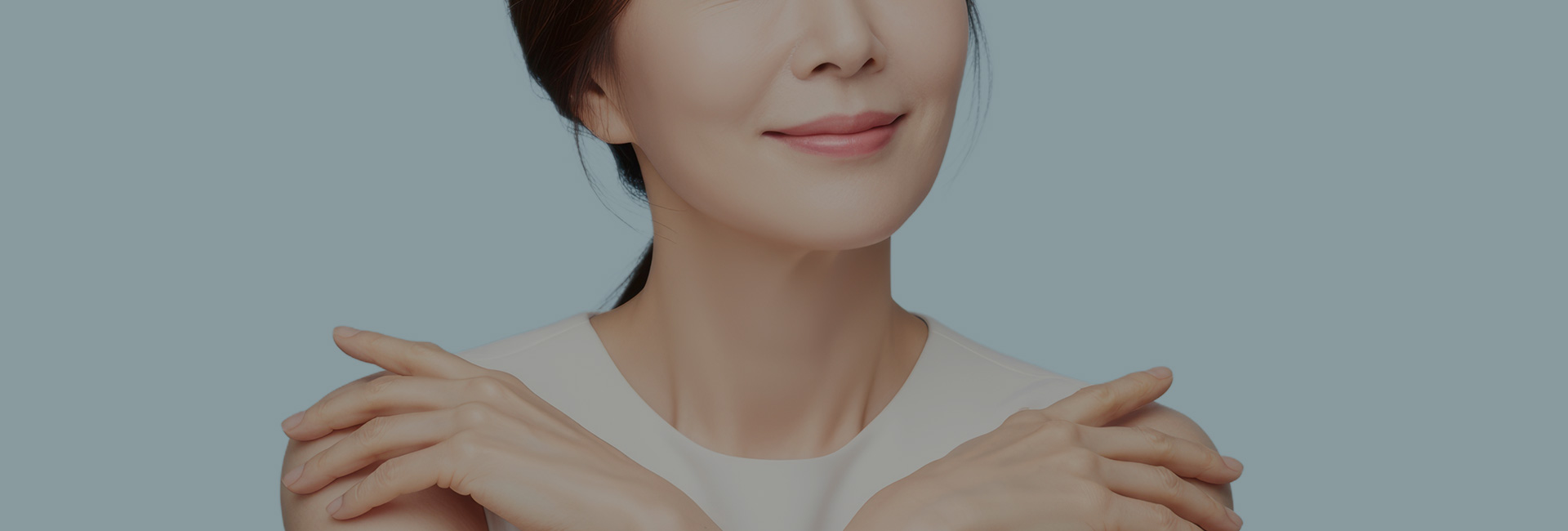 양팔을 교차해 어깨에 손을 올리고 미소 짓는 여성