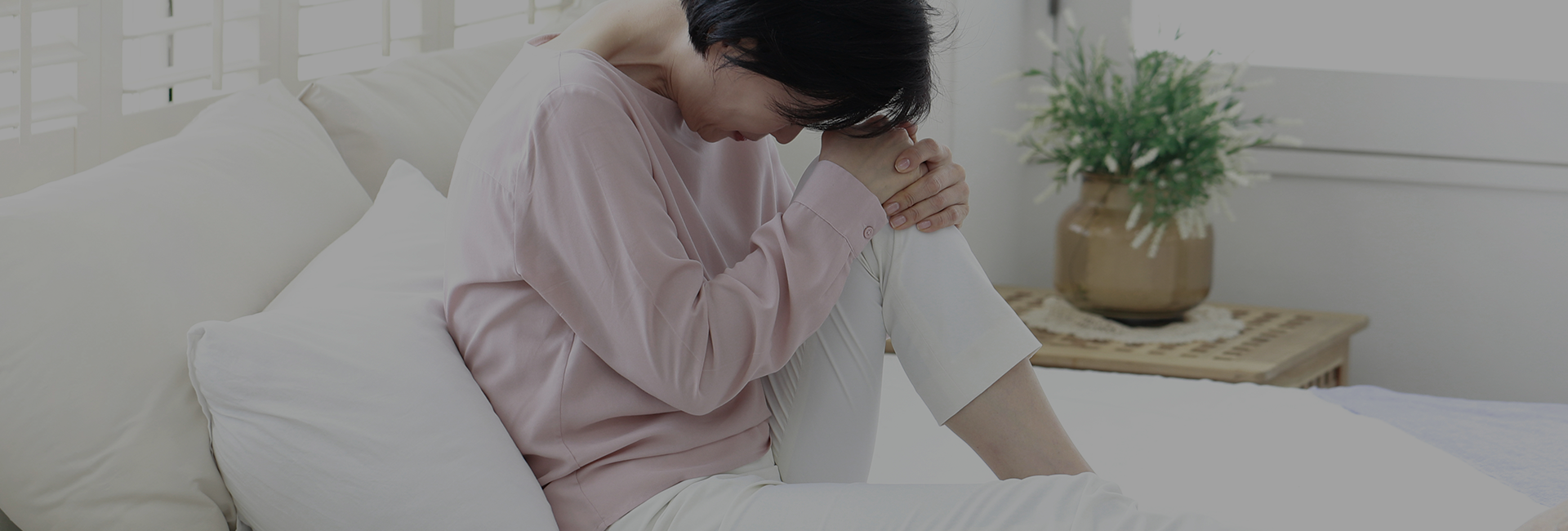 소파에 앉아 무릎을 끌어안고 고개를 숙인 여성