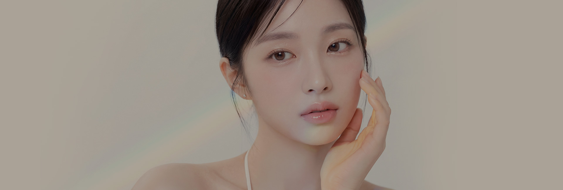 머리를 뒤로 묶고 한 손을 얼굴 옆에 댄 여성